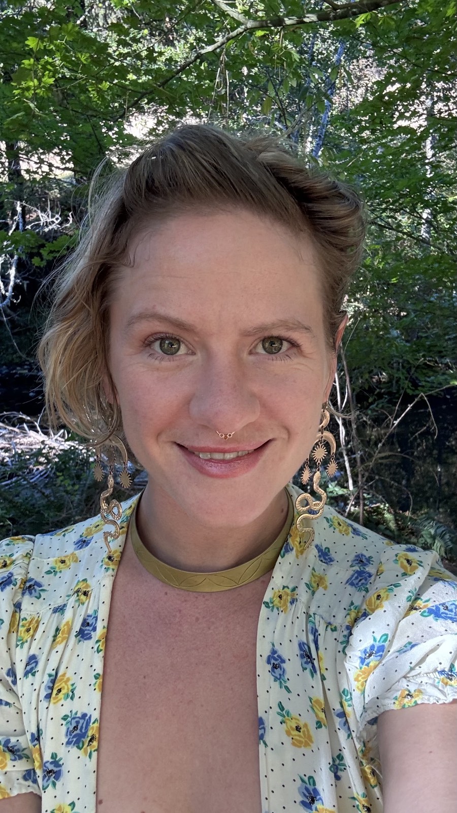 Sasha smiling among green forest leaves