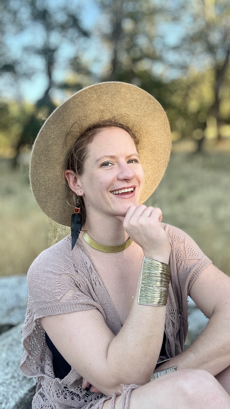 Sasha in a wide-brimmed hat, smiling, with golden evening light behind her